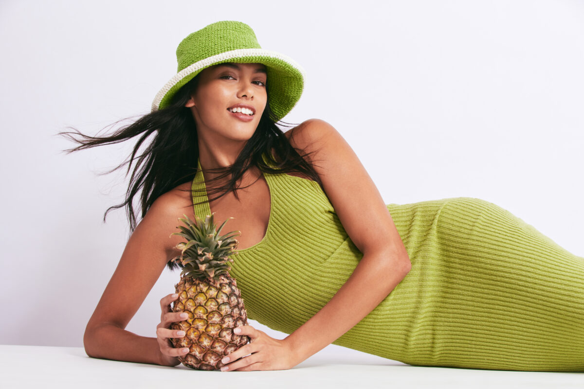Model in green dress holding pineapple